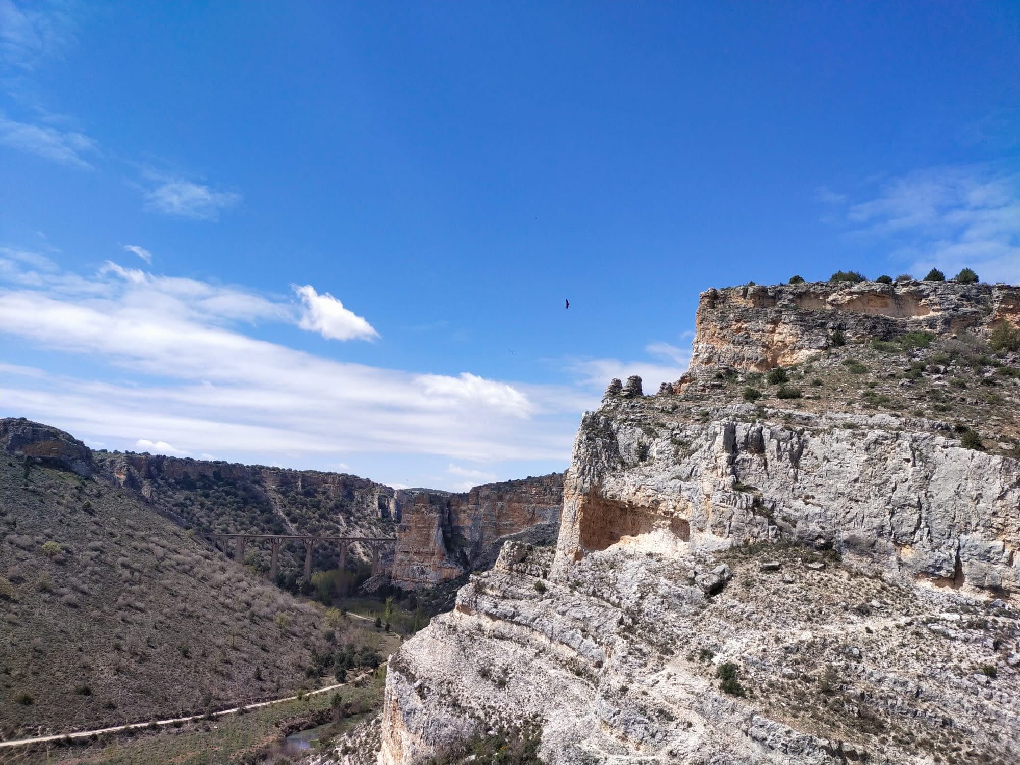 Imponentes acantilados rocosos y un cañón profundo bajo un cielo azul despejado.